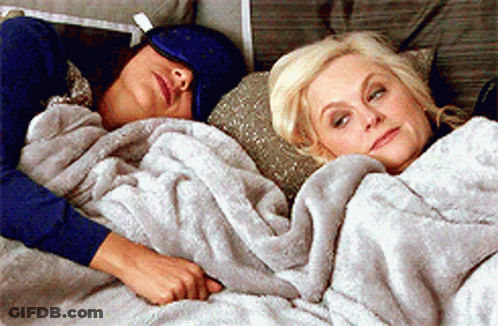 Two Women Lying In Bed Under Blanket GIF
