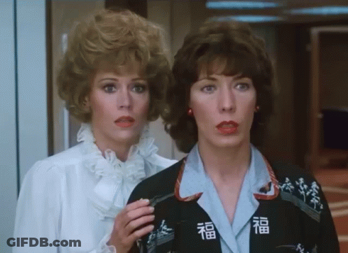 Two Women Next To Each Other One Wearing Jacket With Chinese Characters GIF