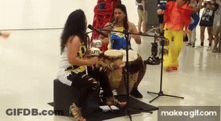 Two Women Playing Drums And Singing Into Microphones GIF