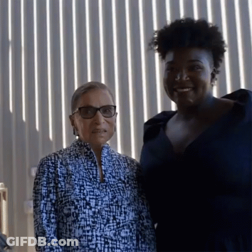 Two Women Posing For A Picture In Front Of A Wall Of Lights GIF