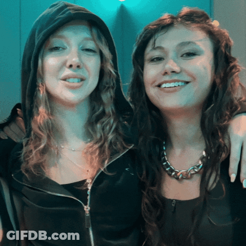 Two Women Posing, One In Black Hoodie GIF