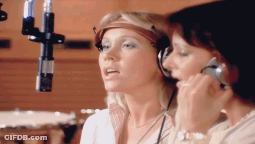 Two Women Singing Into A Microphone With Headphones On GIF