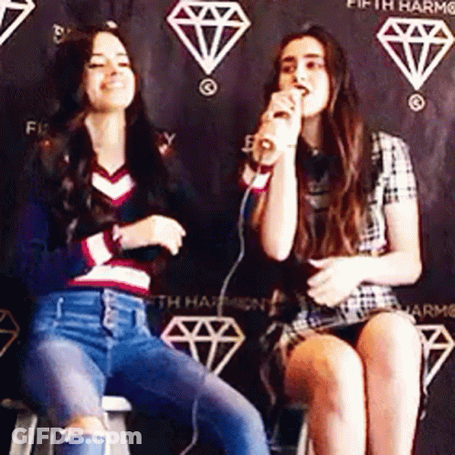 Two Women Singing Into Microphone On Stools GIF