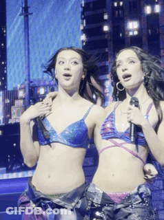 Two Women Singing Into Microphones In Bikini Tops GIF