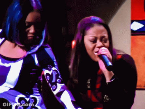 Two Women Singing Into Microphones One In Purple Dress GIF