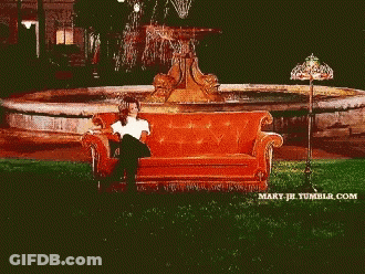 Two Women Sit On A Couch In Front Of A Fountain GIF
