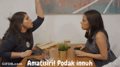 Two Women Sitting At A Table With The Words Amatisii Podak Innuh GIF