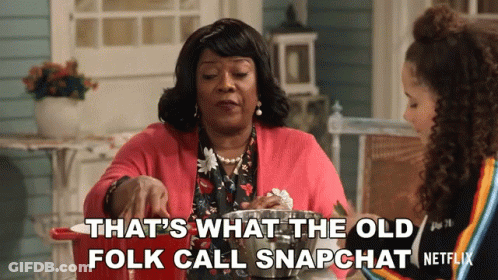 Two Women Sitting At A Table With The Words That 'S What The Old Folk Call Snapchat Written On The Bottom GIF