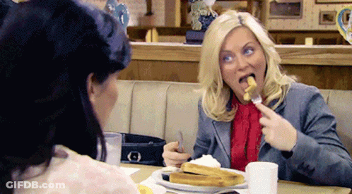Two Women Sitting At Table Eating French Fries GIF