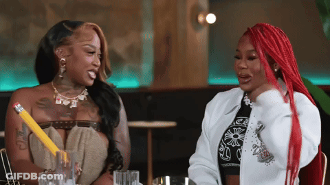 Two Women Sitting At Table With Pencil GIF