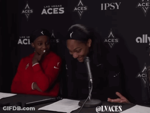 Two Women Sitting In Front Of Aces Wall GIF