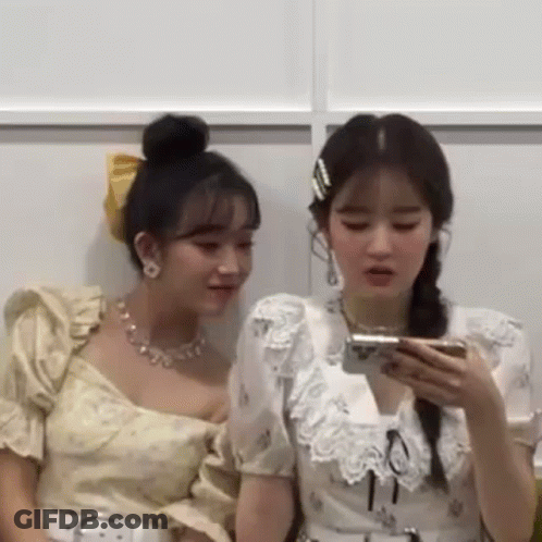 Two Women Sitting Looking At Phones GIF