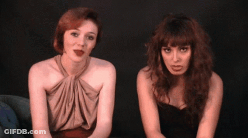 Two Women Sitting Next To Each Other One Wearing Lipstick GIF