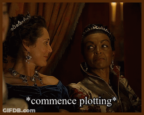 Two Women Sitting Next To Each Other With The Words Commence Plotting Written Below Them GIF