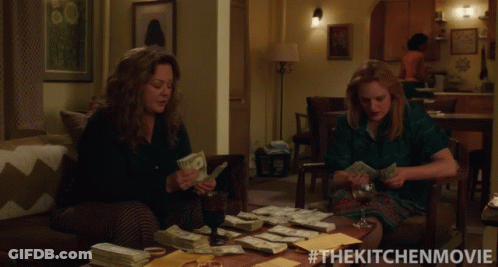 Two Women Sitting On A Couch Counting Money With The Kitchen Movie Written On The Bottom GIF