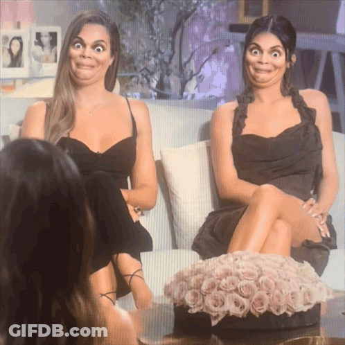 Two Women Sitting On A Couch With Their Legs Crossed Making Funny Faces GIF