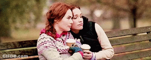 Two Women Sitting On Bench Holding Coffee GIF