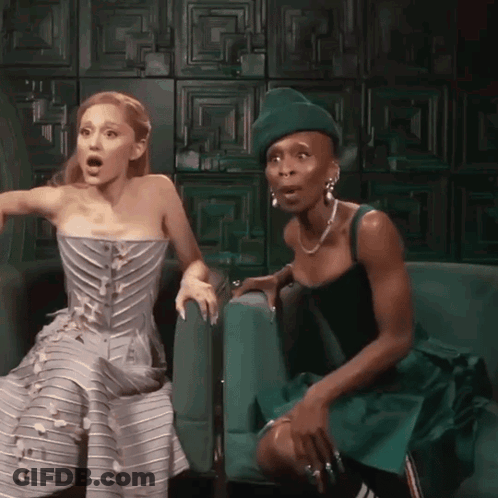 Two Women Sitting On Green Couch GIF