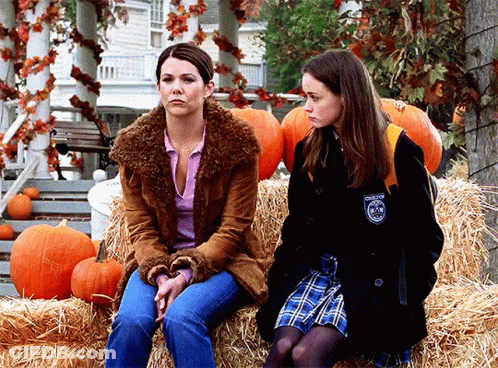 Two Women Sitting On Hay Bale With Pumpkins And Chester Patch GIF