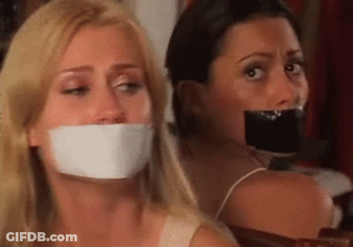 Two Women Sitting With Mouths Taped GIF