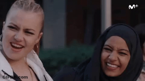 Two Women Smiling And Laughing In Front Of M+ Sign GIF