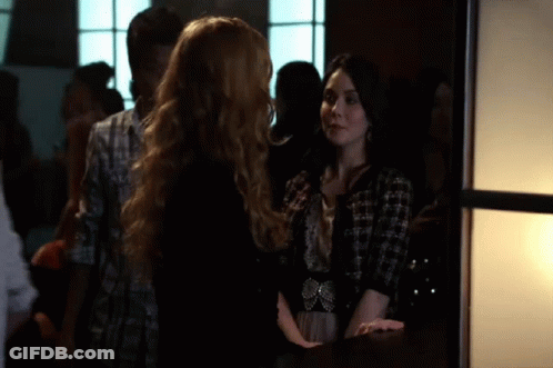 Two Women Standing In Crowded Room Talking GIF