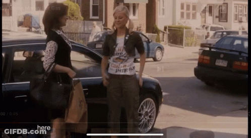 Two Women Standing In Front Of A Car With The Word Here On The Bottom GIF