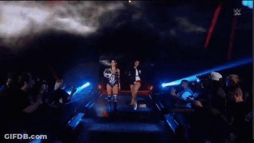 Two Women Standing In Front Of A Sign That Says Evolve Womens Champion Kendal Grey GIF
