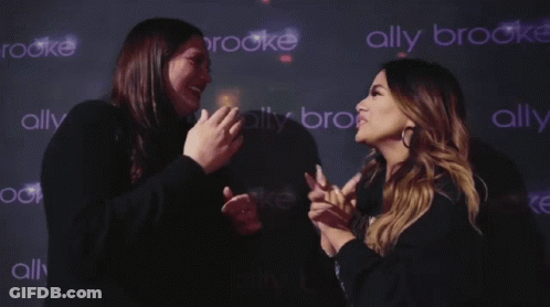 Two Women Standing In Front Of Ally Brooke Wall GIF