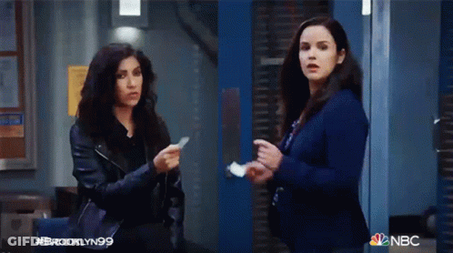 Two Women Standing In Front Of Blue Door Holding Paper GIF