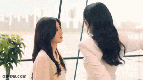 Two Women Standing In Front Of Office Window GIF
