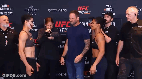 Two Women Standing In Front Of UFC Sign GIF