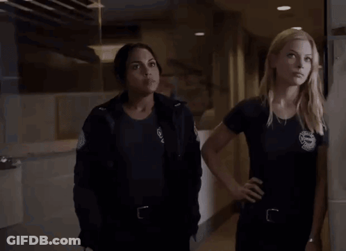 Two Women Standing In Hallway Looking At Something GIF