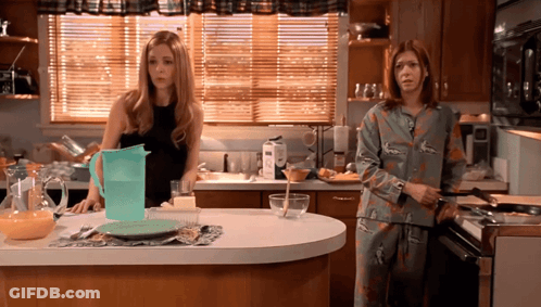 Two Women Standing In Kitchen With Pitcher Of Water GIF