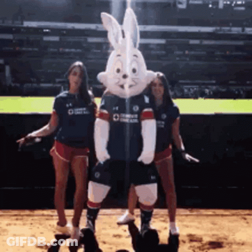 Two Women Standing Next To A Bunny Mascot Wearing A Blue Shirt That Says Comcast GIF