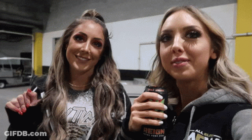Two Women Standing Next To Each Other Holding A Can Of Reign Energy Drink GIF