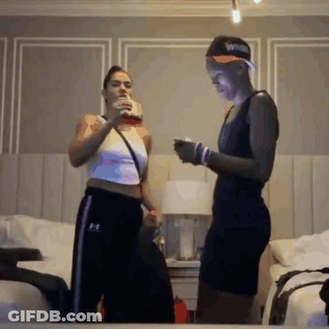 Two Women Standing Next To Each Other In A Bedroom Wearing Under Armour Sweatpants GIF