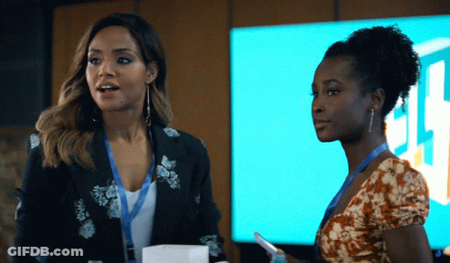 Two Women Standing Next To Each Other In Front Of A Sign That Says ' Jl ' On It GIF