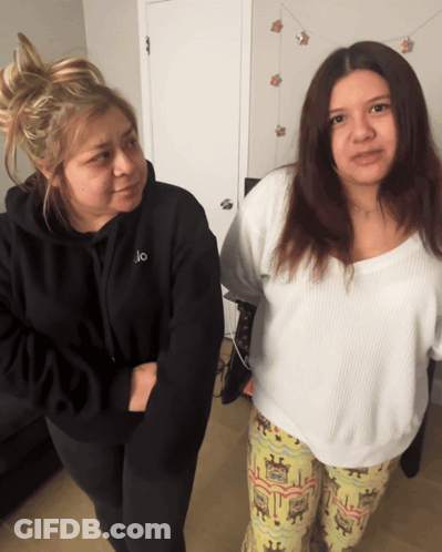 Two Women Standing Next To Each Other One Wearing A Black Hoodie With The Letter O On It GIF