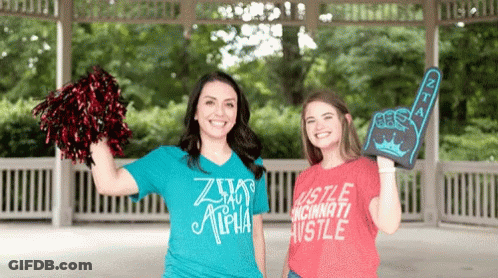 Two Women Standing Next To Each Other One Wearing A Shirt That Says Hustle Cincinnati Hustle GIF