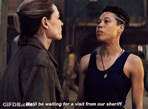 Two Women Standing Next To Each Other Saying We'll Be Waiting For A Visit From Our Sheriff GIF