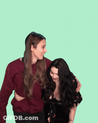 Two Women Standing Next To Each Other With One Wearing A Maroon Sweater GIF