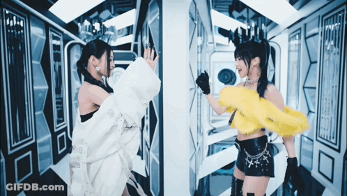 Two Women Standing Next To Each Other With One Wearing A Yellow Top GIF