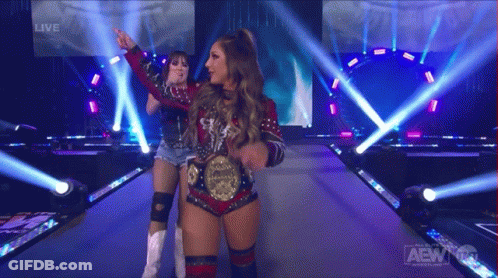 Two Women Standing On Stage With AEW Logo GIF