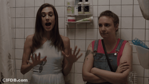 Two Women Talking In Bathroom With I Love You Tattoo GIF