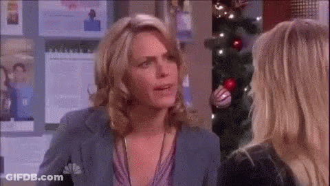 Two Women Talking In Front Of Christmas Tree GIF