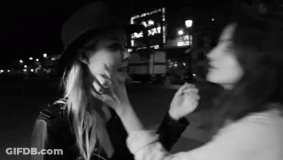 Two Women Touching Faces At Night GIF