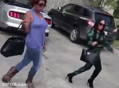 Two Women Walking Down Street Past Parked Car GIF