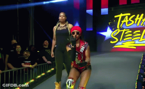 Two Women Walking On Stage With Stash Steel Sign GIF