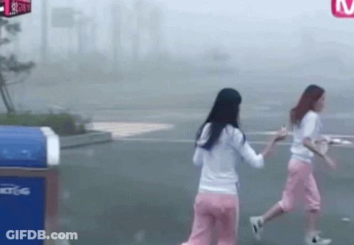 Two Women Walking Past Sign Saying M GIF